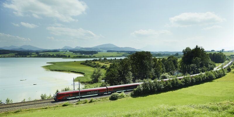Railjets in Landschaft vor einem See